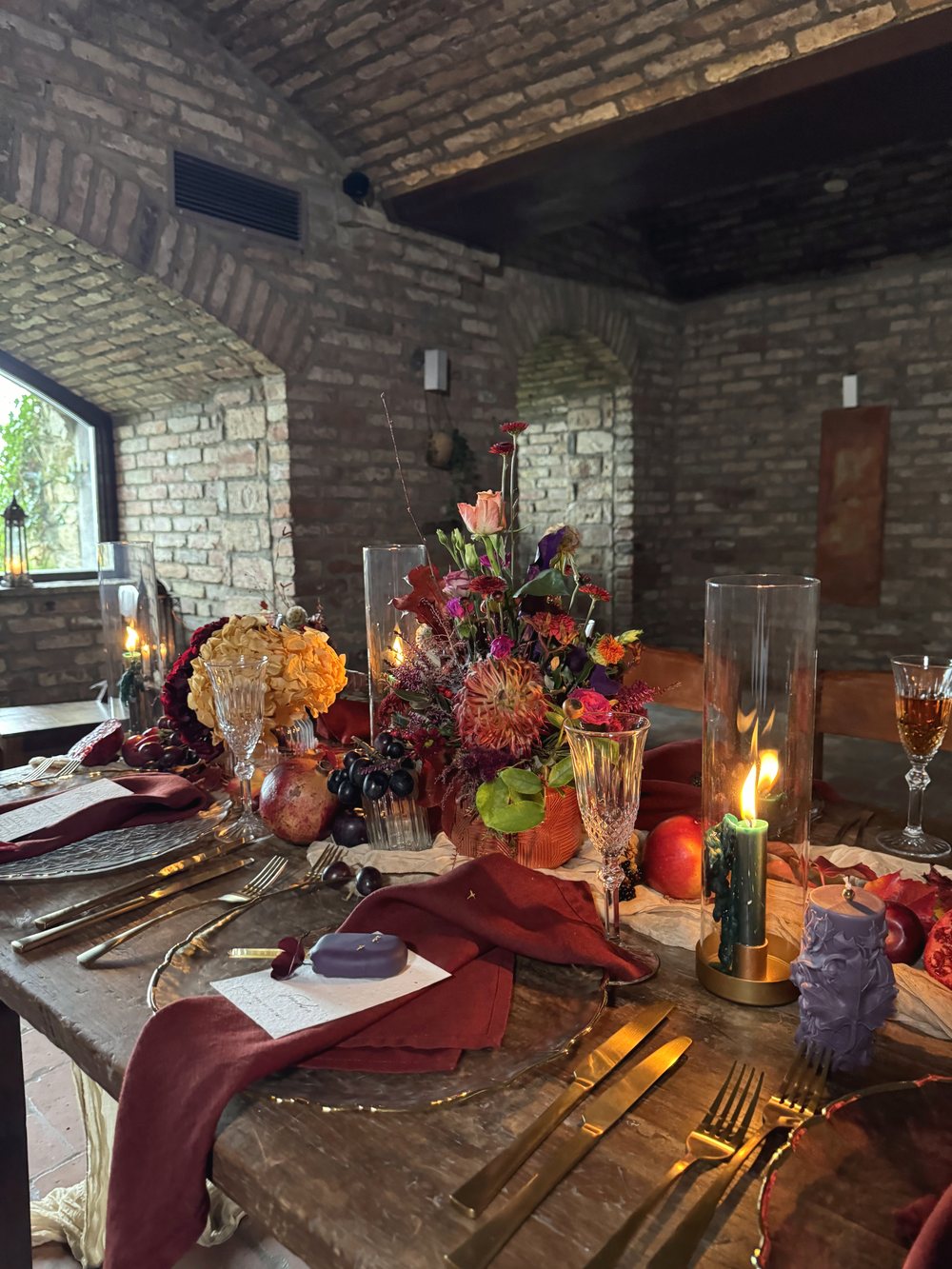Festliche Tafel mit Bordeaux-Servietten, Kerzen und Gestecken in Orange und Bordeaux