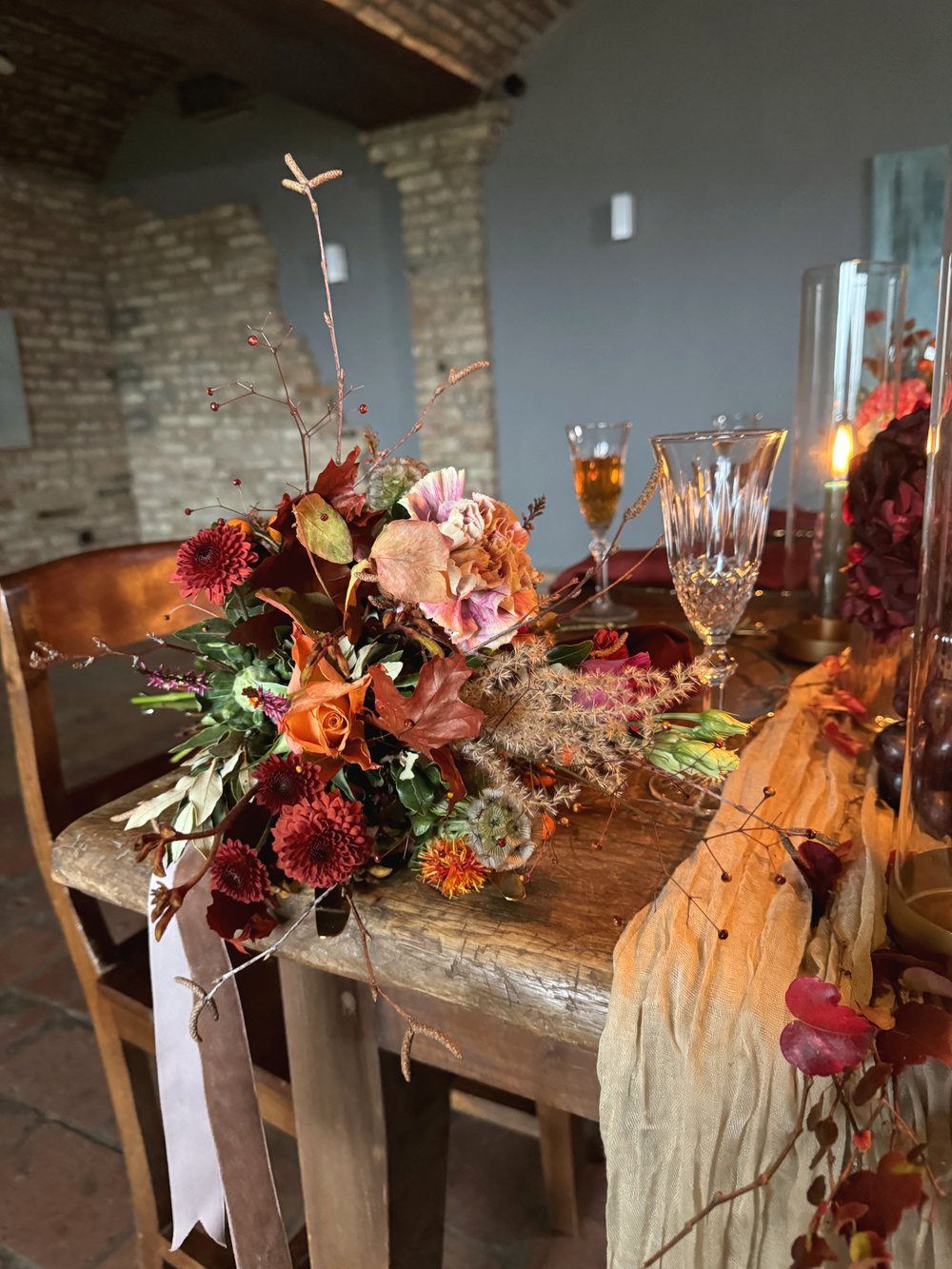 Herbstlicher Strauß in Orange und Bordeaux auf einer festlich gedeckten Tafel